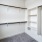Bright white room featuring a closet with built-in shelves, providing organized storage space