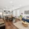 A stylish living room and kitchen area in a modern apartment, with soft white walls, and contemporary furnishings