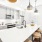 A modern kitchen featuring stainless steel appliances, soft gray cabinets and a white counter top