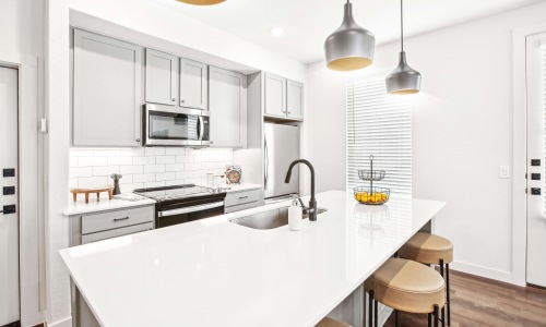 Modern kitchen with a large island, stainless steel appliances, and pendant lighting in a San Antonio townhome.