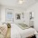 An inviting bedroom displays a clean white-green bed with cozy pillows, alongside a generous window blinds