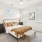 A cozy bedroom with a white bed, brown dresser, and a window blinds