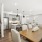 A warm kitchen and dining room featuring rich hardwood floors, white cabinetry, and a wooden dining table set 