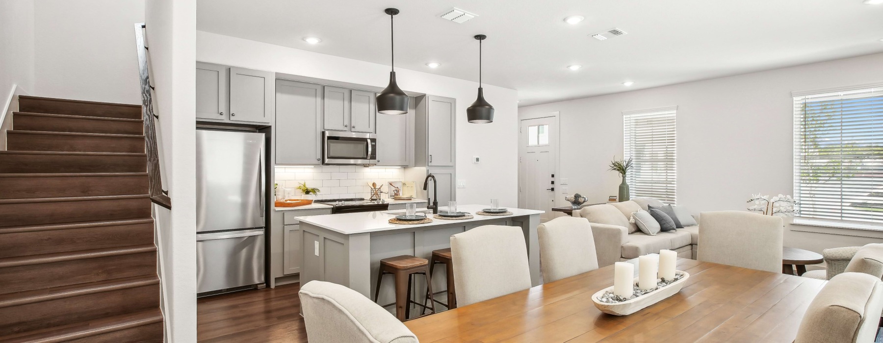 Modern kitchen and dining area inside a 3-bedroom townhome in San Antonio, featuring stainless steel appliances, spacious island, and open-concept living space.