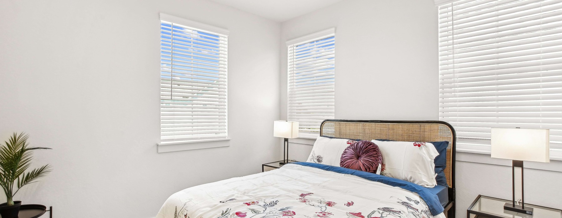 Bright primary bedroom in Two Bedroom townhomes San Antonio featuring large windows, modern furnishings, and abundant natural light.