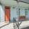 An inviting porch featuring a bench and bright orange door